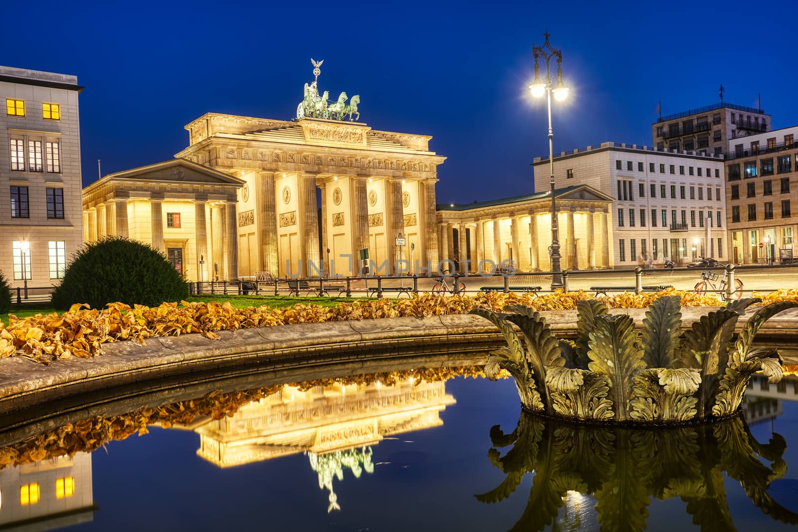 The famous Brandenburger Tor in Berlin at night, reflected in a fountain