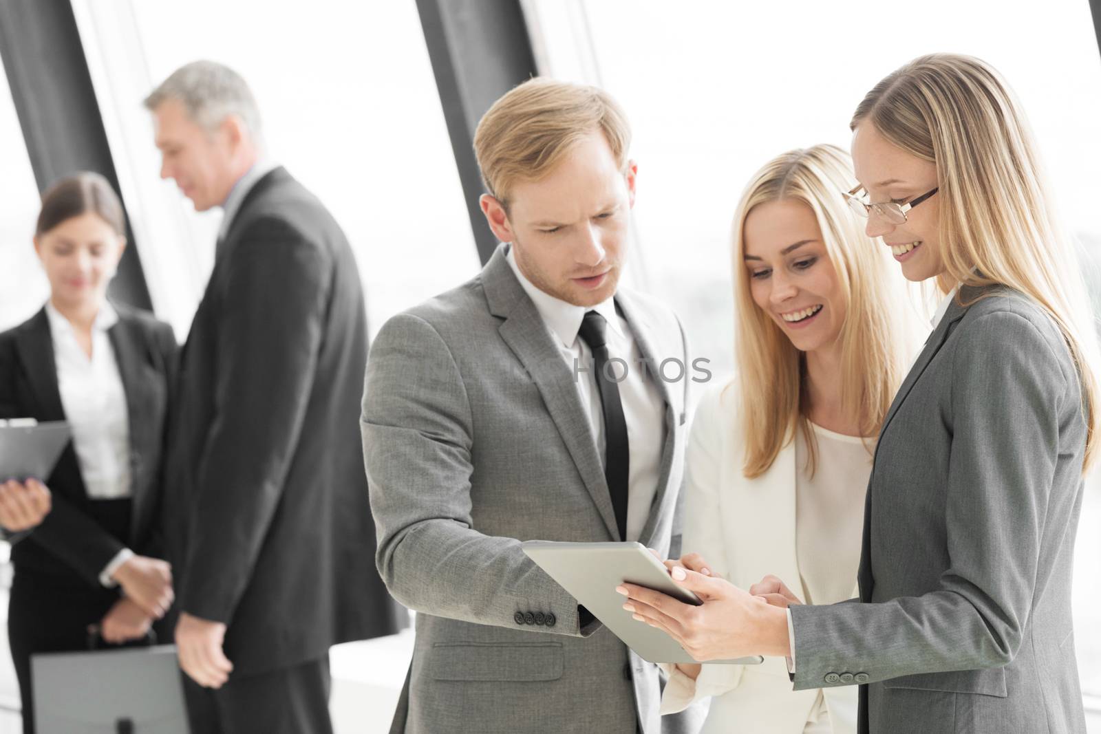 Three smart employees discussing documents using tablet pc at meeting