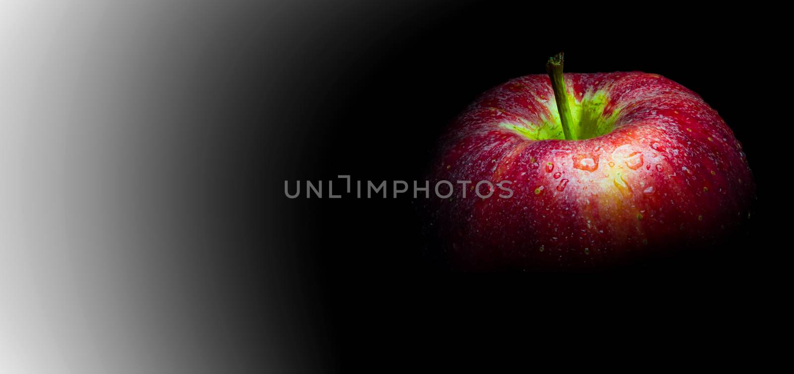 Water droplet on glossy surface of red apple on black background by Satakorn