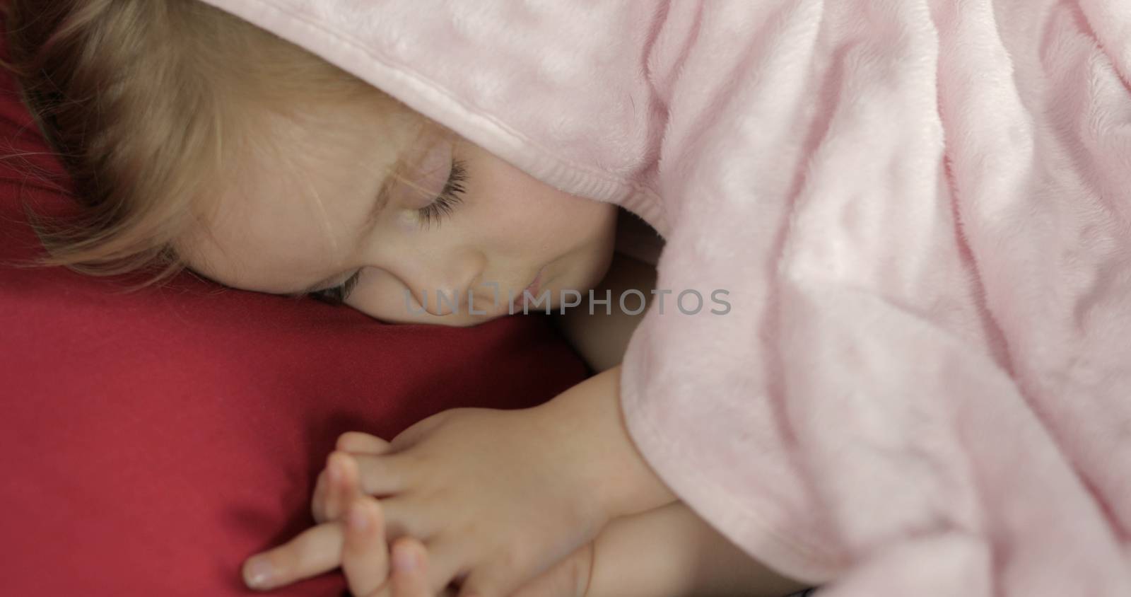 Cute baby girl sleeping on cozy bed at home. Pretty, little girl sleeping in morning light. Close-up portrait of child naps. Concept of peaceful sweet dreams