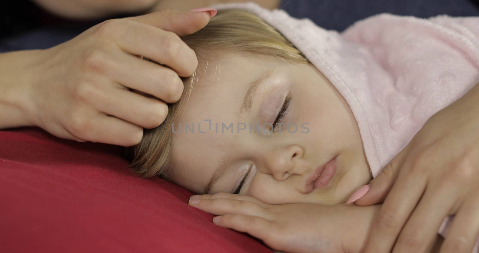 Young mother taking care of her little baby girl while she sleep. Girl sleeping on cozy bed at home. Pretty girl sleeping in morning light. Close-up portrait of child naps. Concept of peaceful dreams