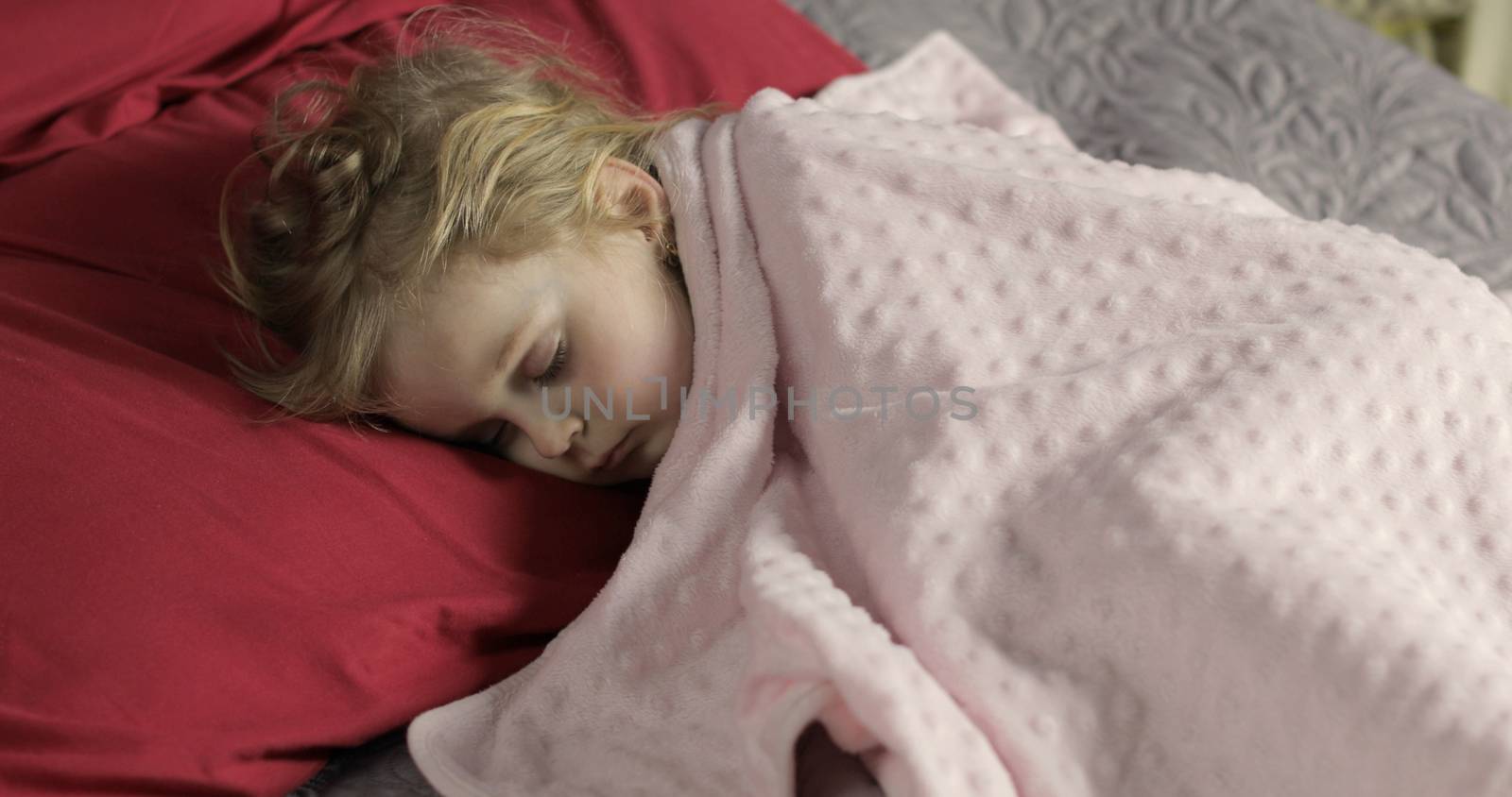 Cute baby girl sleeping on cozy bed at home. Pretty, little girl sleeping in morning light. Close-up portrait of child naps. Concept of peaceful sweet dreams