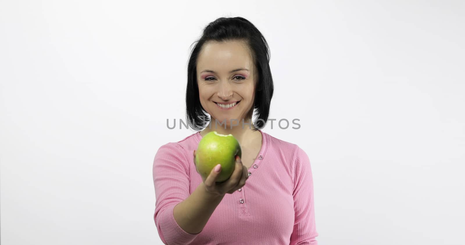 Young beautiful with green apple offer bite to viewer. Healthy nutrition.