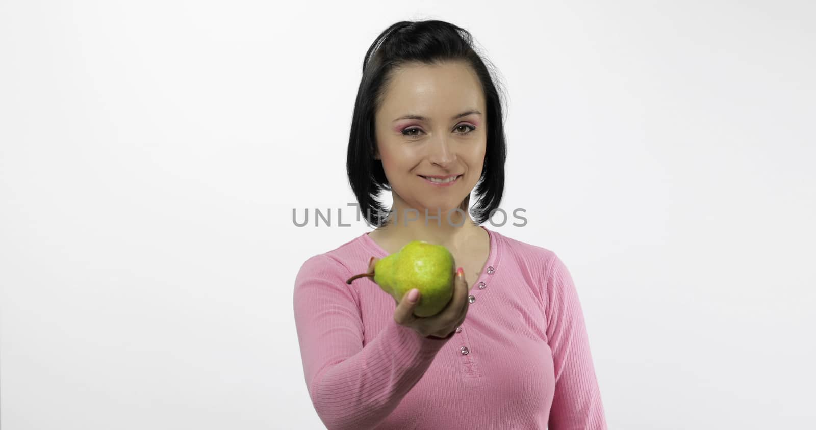 Young beautiful woman with big, fresh, juicy, green pear. Offer bite to viewer. Healthy nutrition