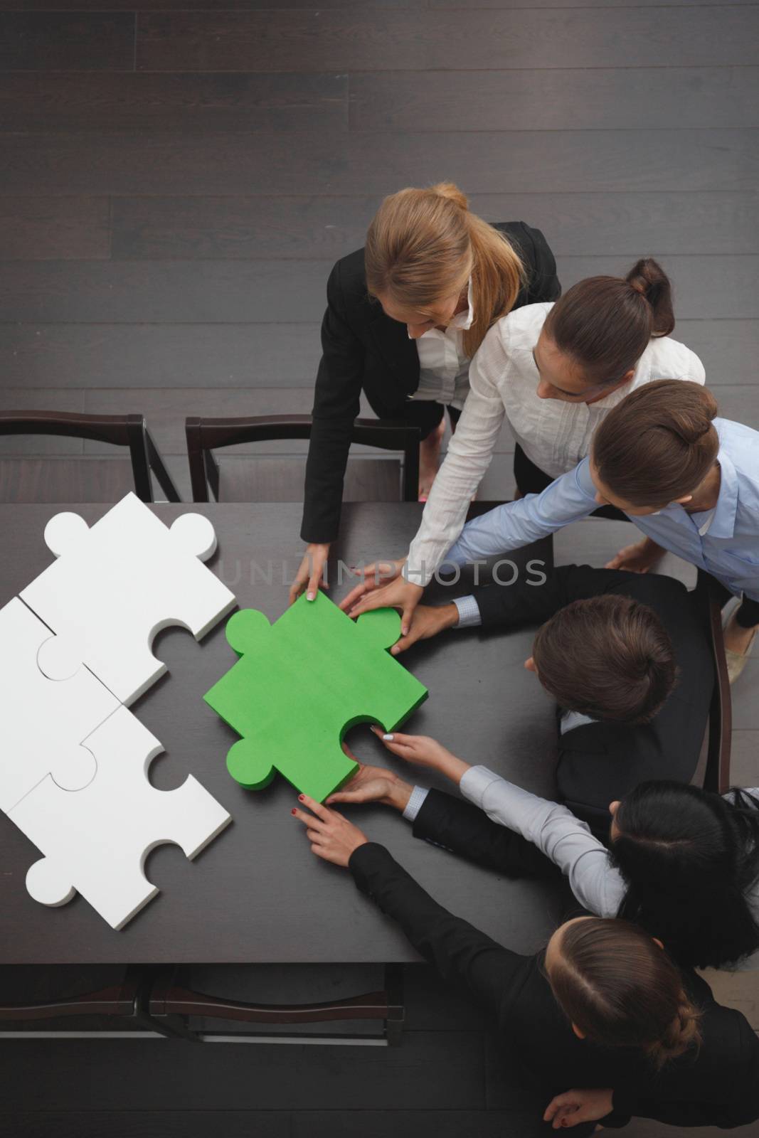 Group of business people assembling final piece of jigsaw puzzle, team work support unity cooperation and help concept