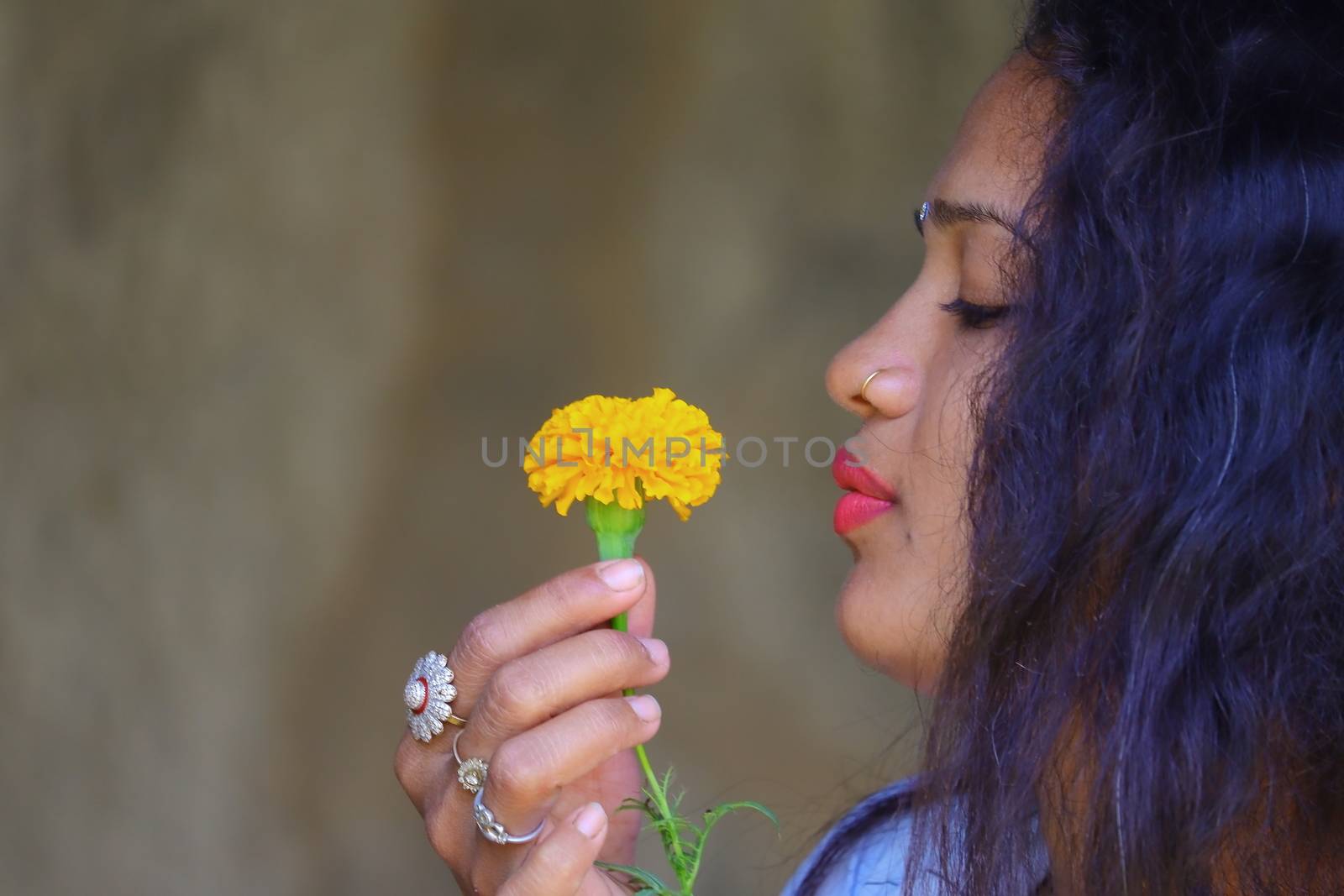 side view of a young girl holding yellow marigold flower and copy space background