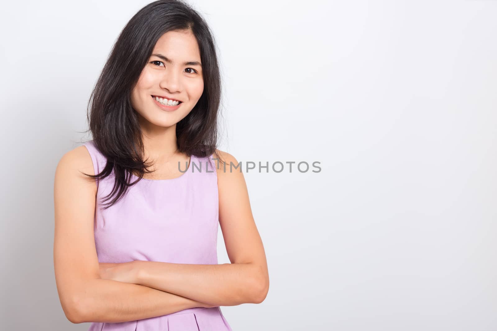 Portrait Asian beautiful young woman standing smile seeing white teeth, She crossed her arms and looking at camera, shoot photo in studio on white background. copy space to put text