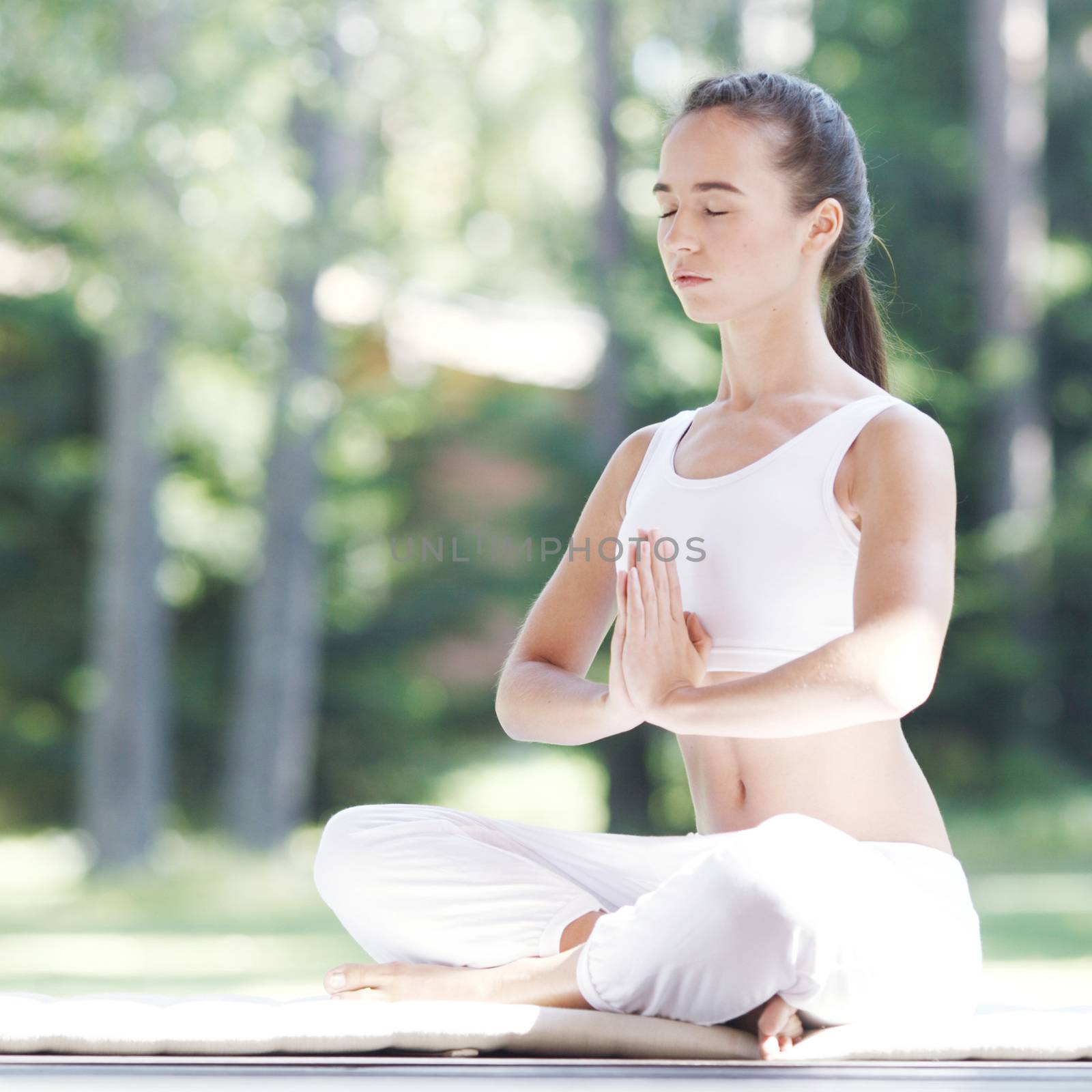 Young woman in white sportswear doing yoga lotus exercise outdoors tranquility peace enjoyment