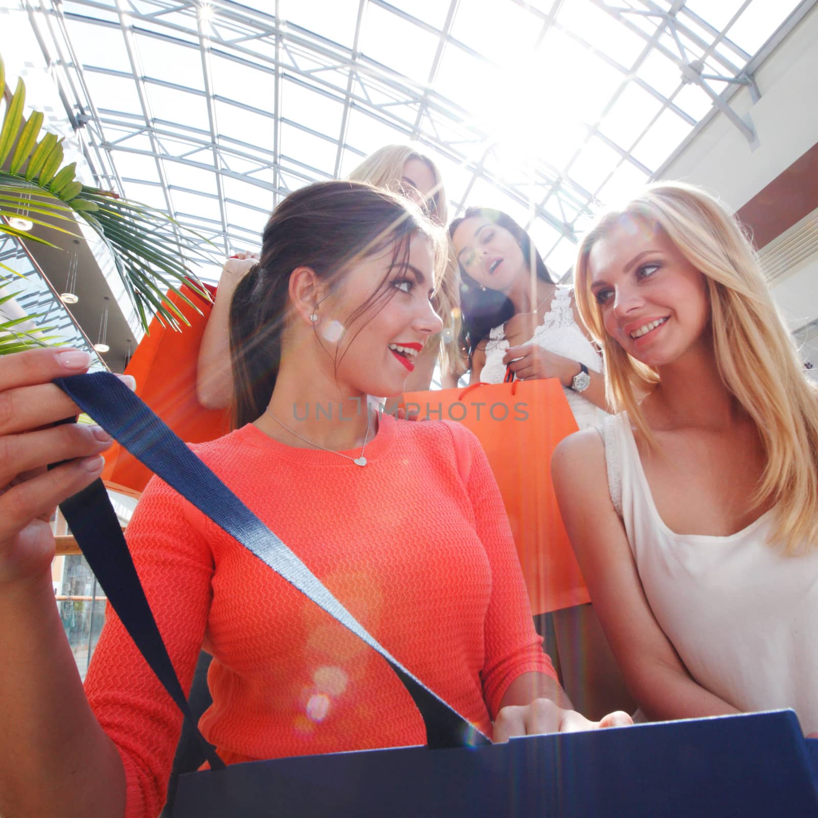 Excited female friends looking inside shopping bag sale concept