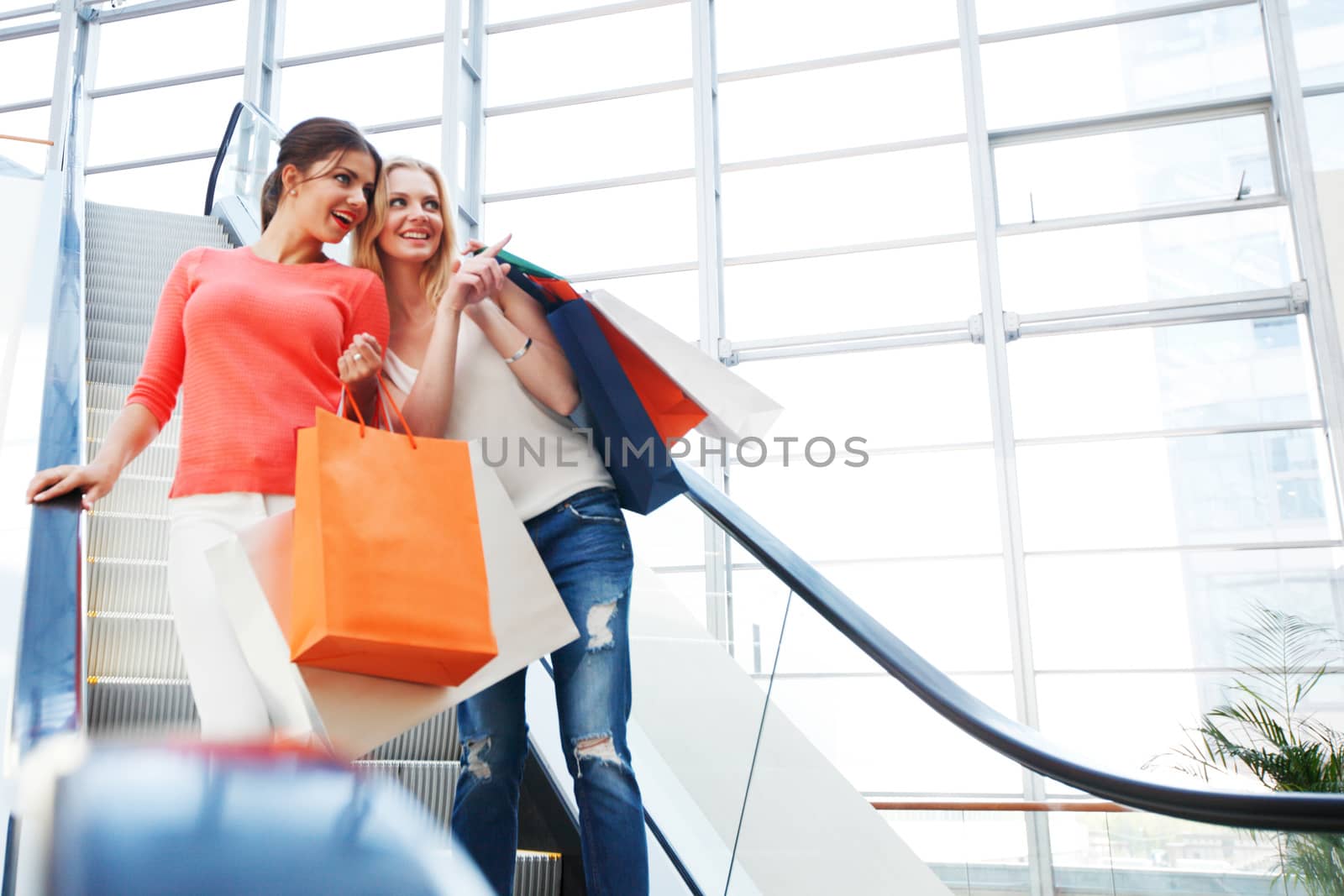 Young girls with shopping bags in shop at escalator