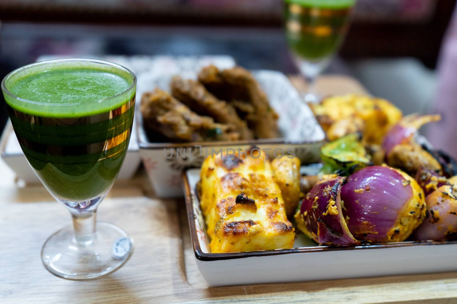 shot of delicious chicken drum sticks legs, lollypop, mutton patties, cottage cheese, mint chutney in glasses for a punjabi north indian barbeque meal. A perfect mix of meat and vegetarian elements in mughal style