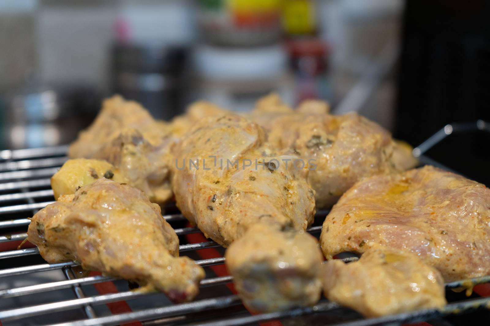 chicken marinated with oil and spices cooking on a hot electric grill making paneer tikka masala in an Indian home by Shalinimathur