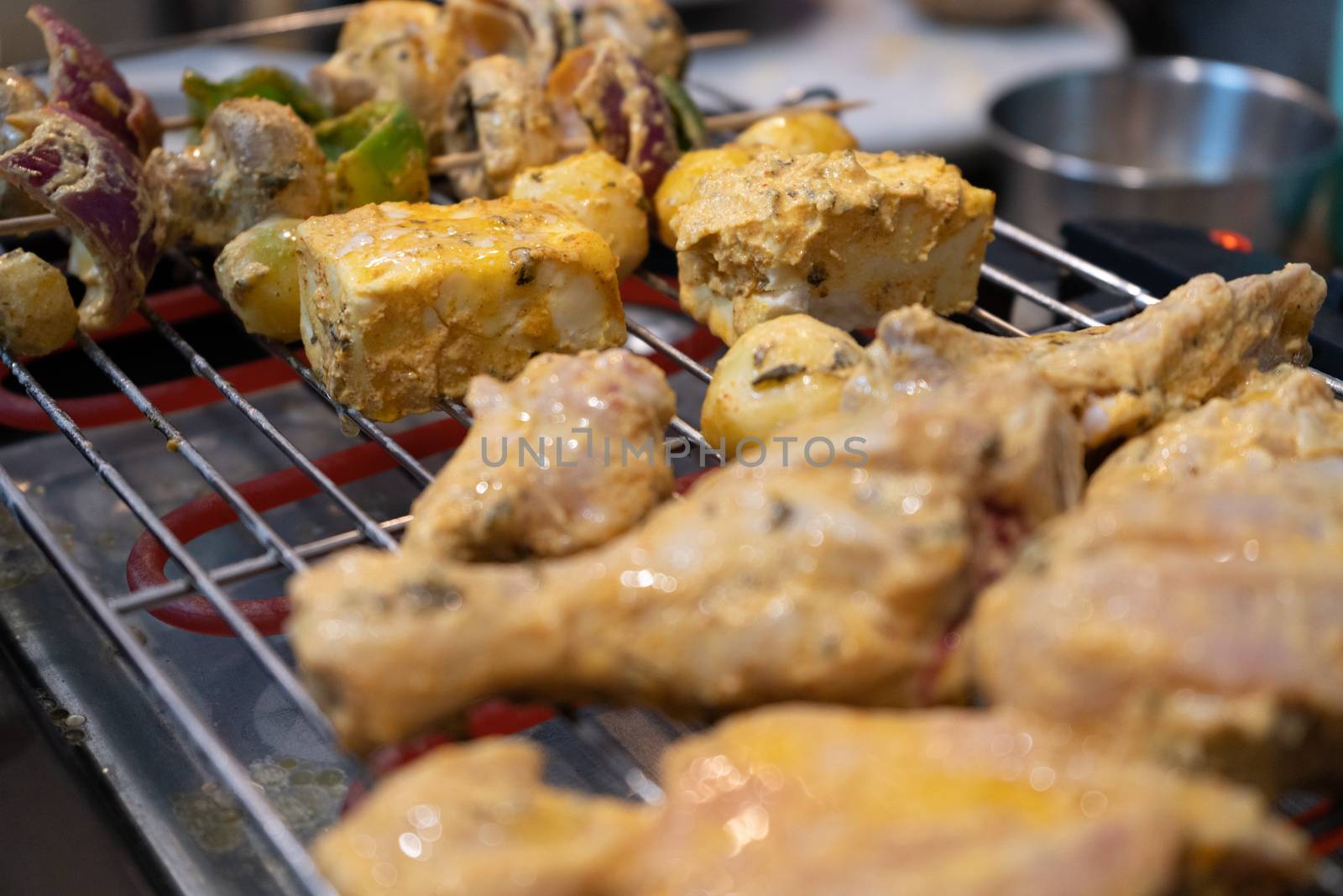 chicken marinated with oil and spices cooking on a hot electric grill making paneer tikka masala in an Indian home. Shows a tasty food that is very popular as a meal or as a snack street food