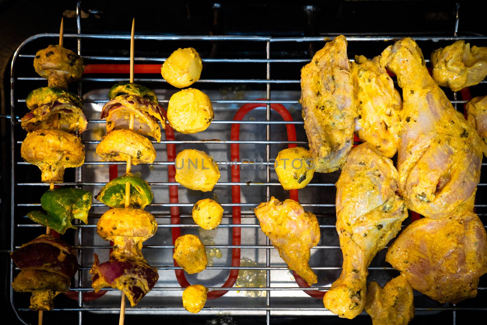 Top flatlay view showing chicken cooking on one side and vegetables cooking on the other over a electric grill . Concept showing the choice of vegetarian or non vegetarian cuisine in a person's life
