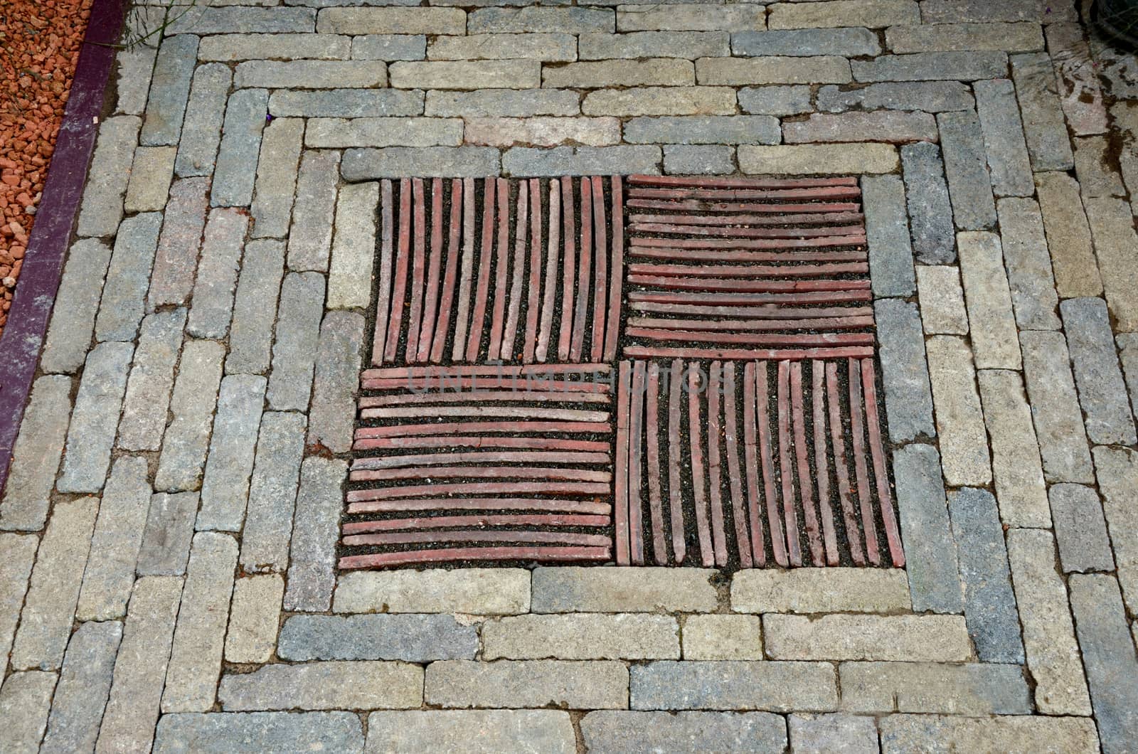 A close up view of decorative mosaic insert of stones bricks and tiles in a garden pathway
