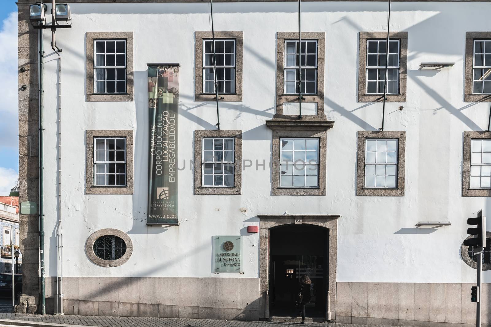 Porto, Portugal - November 30, 2018: Storefront and architectural detail of Lusofona de Porto University in the historic city center where people walk on a winter day