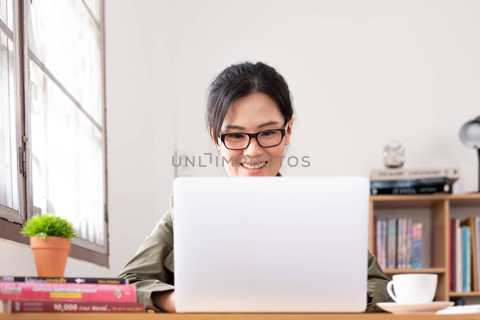 Modern young Asian woman working from home with happy and smile. by animagesdesign