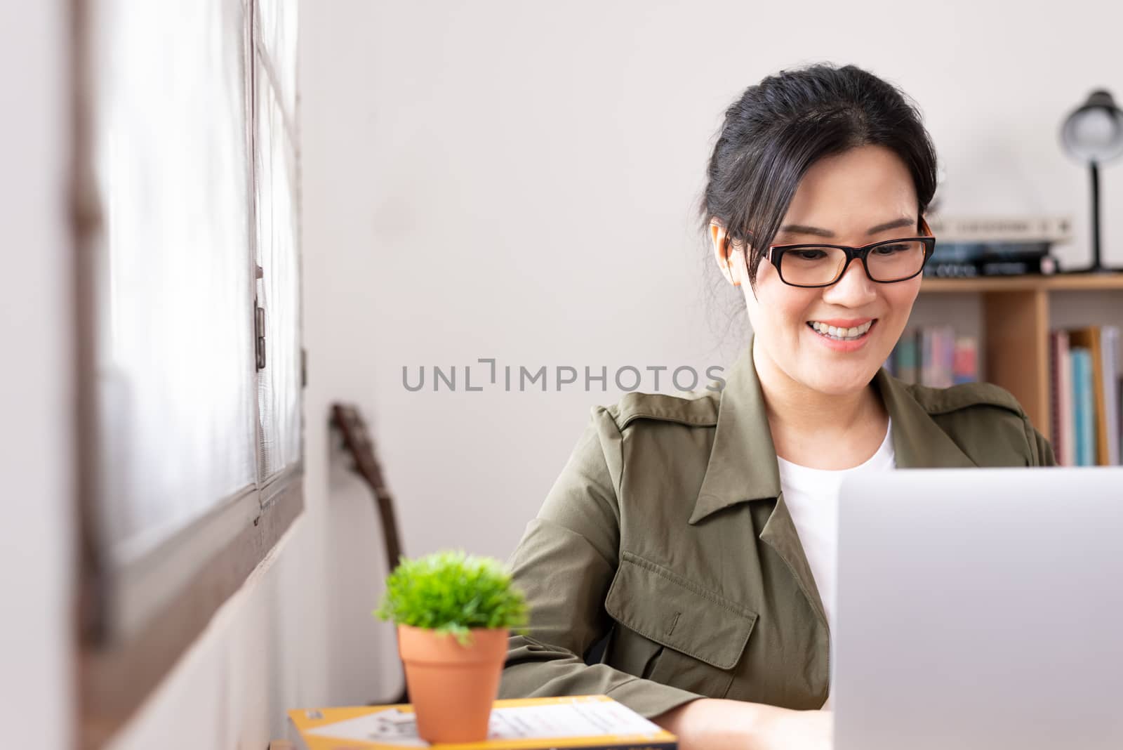 Modern young Asian woman working from home with happy and smile.