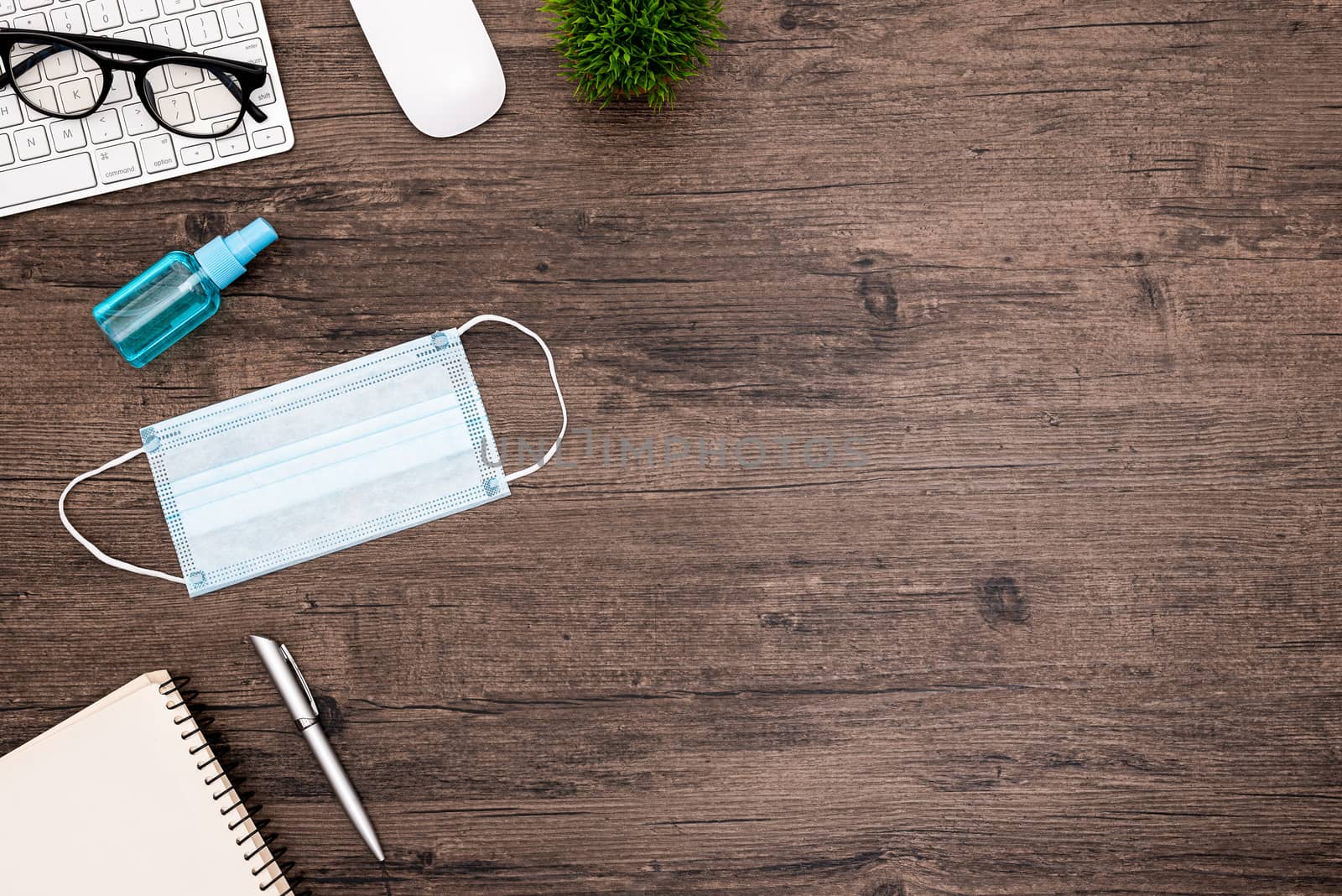 The equipment to protect COVID-19, blue mask and hand cleaner gel for preparing to work from home Isolated on wood desk.