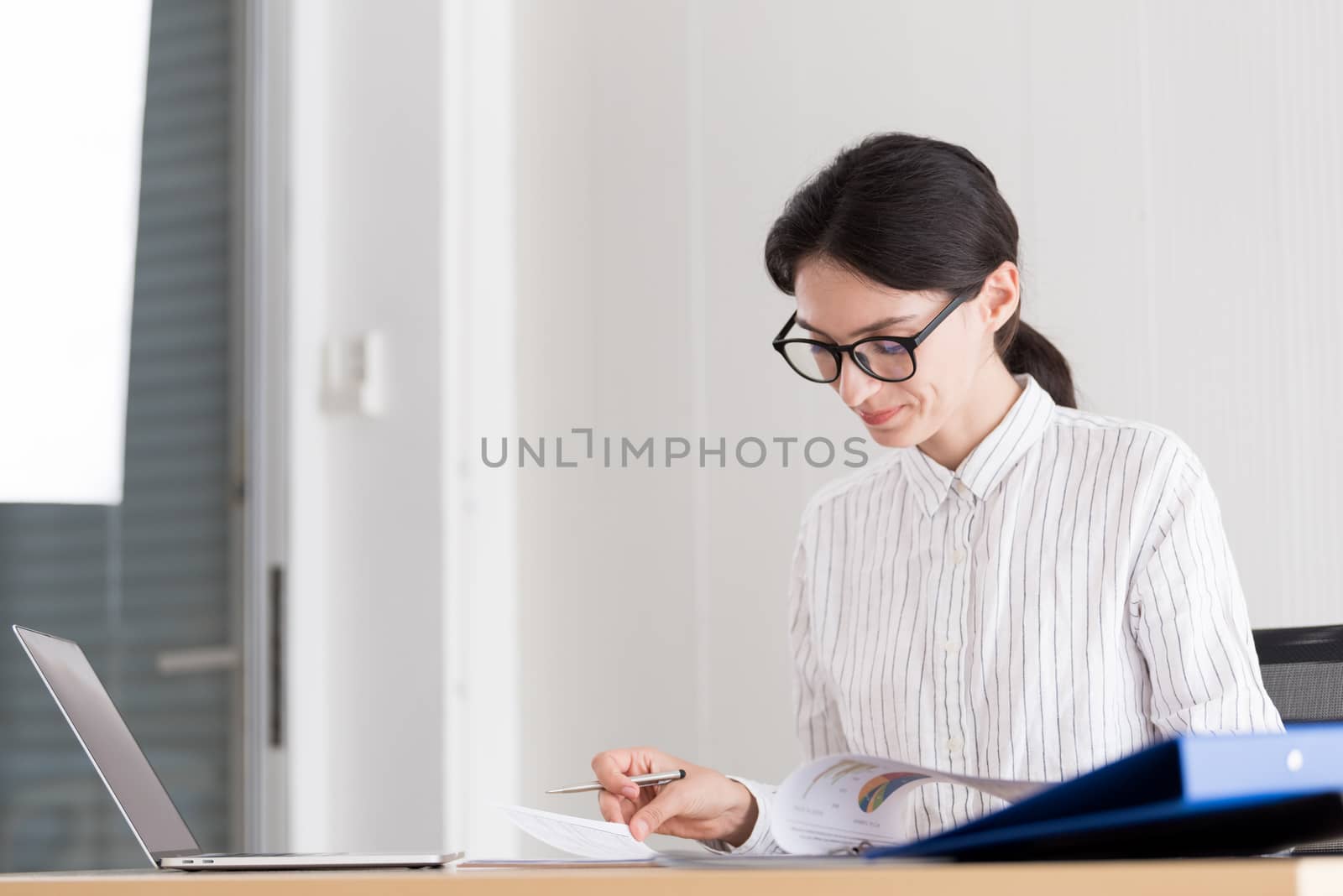 A businesswoman wearing glasses working with smiling and happiness at the office.