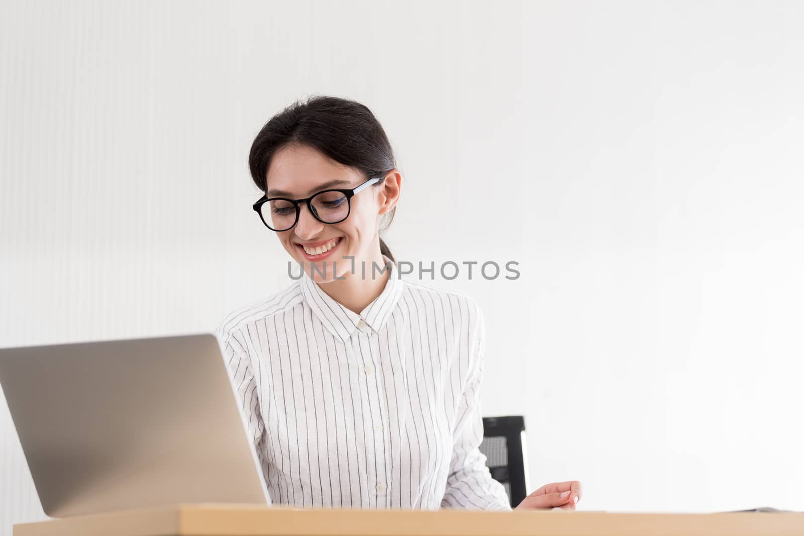 A businesswoman wearing glasses working with smiling and happiness at the office.