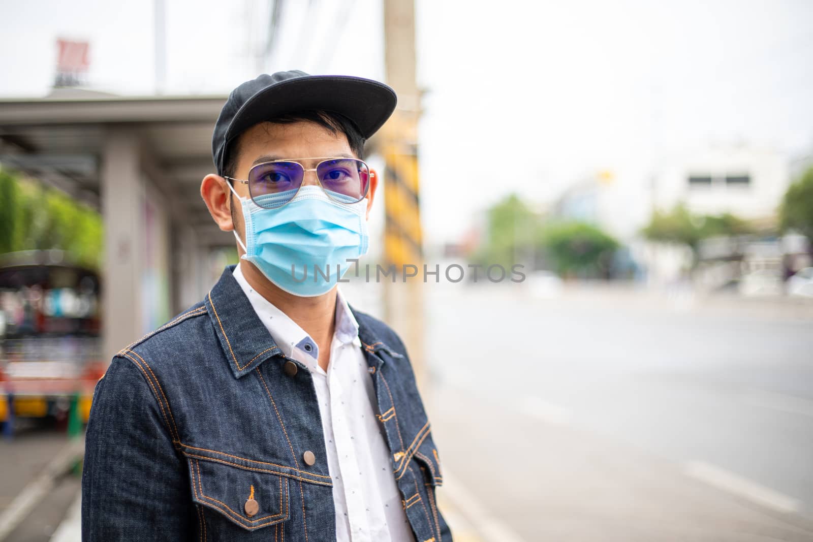 Asian Young man standing in the city and wearing protection mask on face for protection air pollution, particulates and for protection flu virus, influenza, coronavirus at city