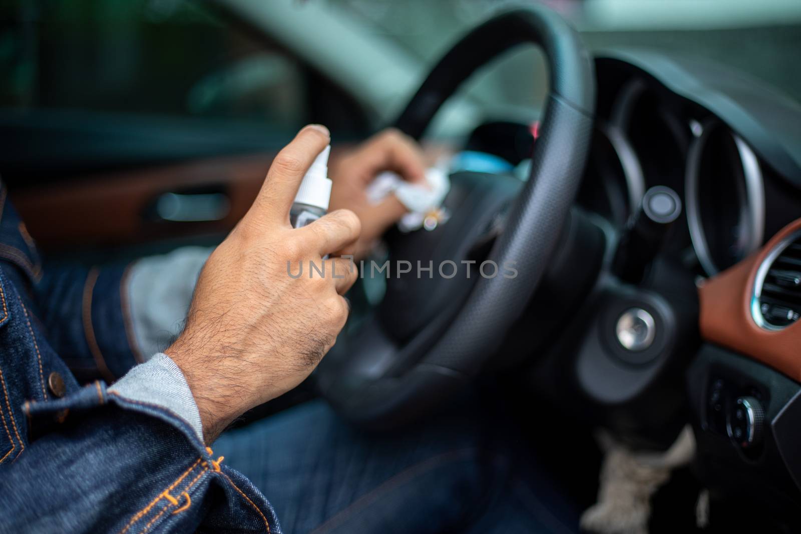 Asian man using spray alcohol to clean the car for coronavirus protection