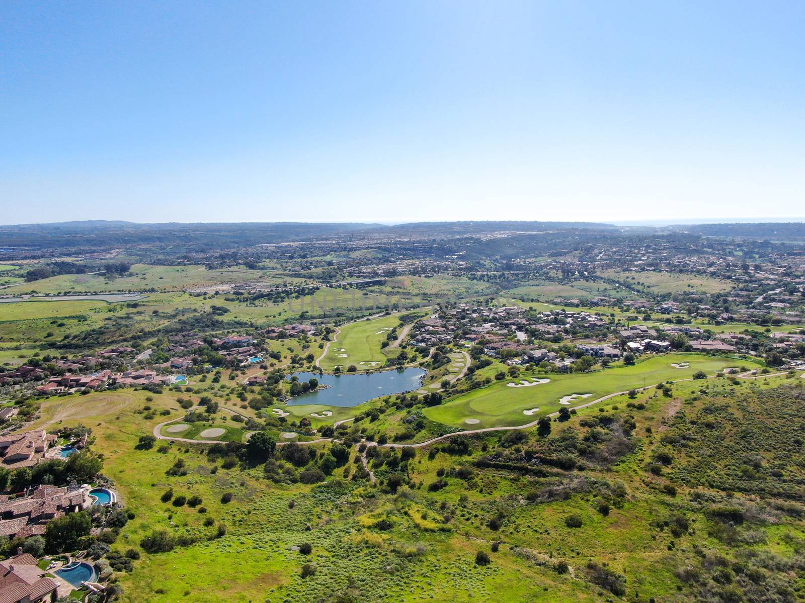 Aerial view of green valley with big luxury villa on the background in a private community by Bonandbon