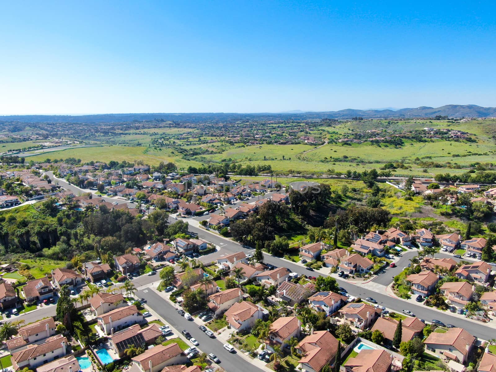 Aerial view of upper middle class neighborhood in the valley with blue sky by Bonandbon