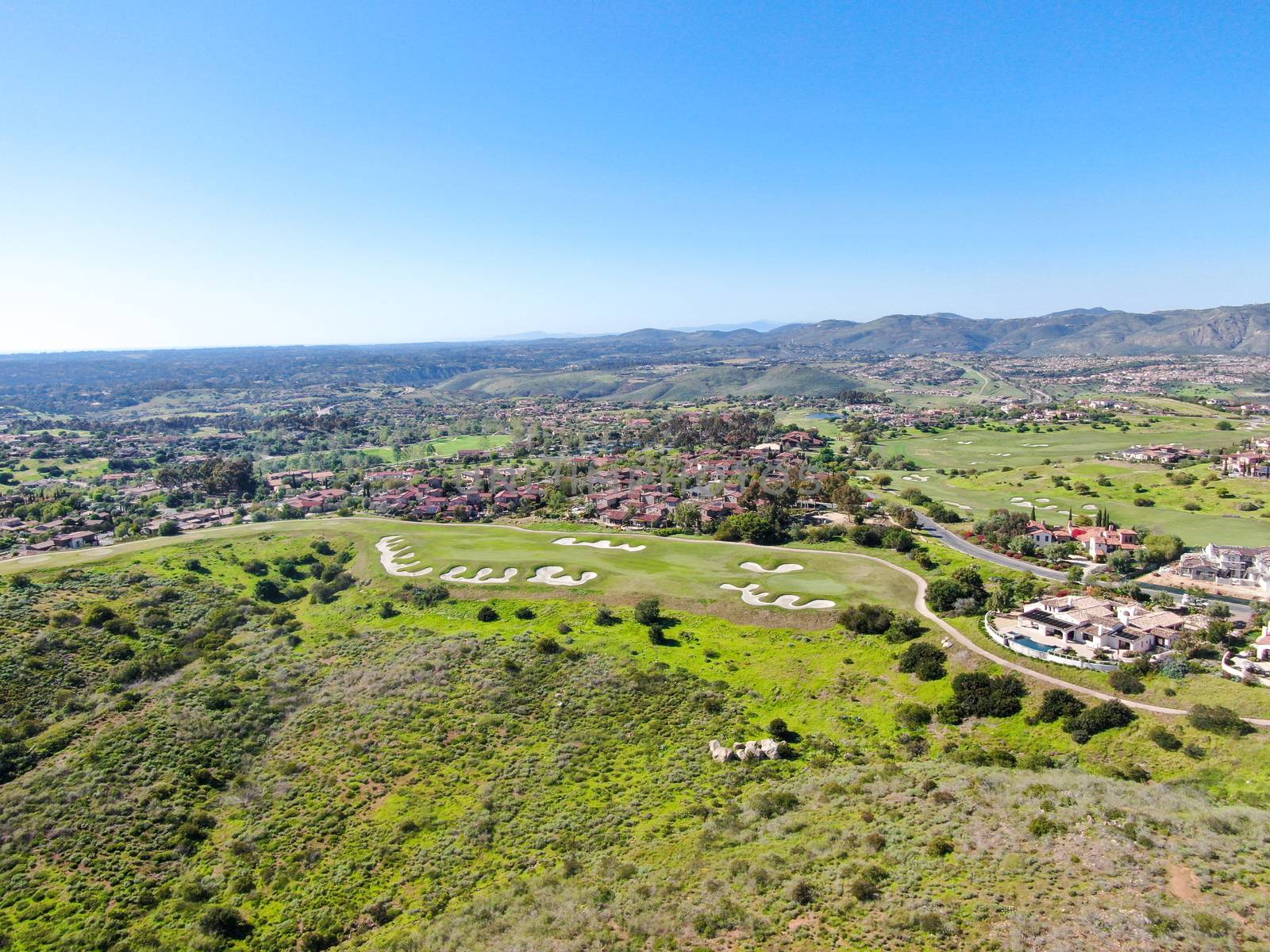 Aerial view of green valley with big luxury villa on the background in a private community by Bonandbon