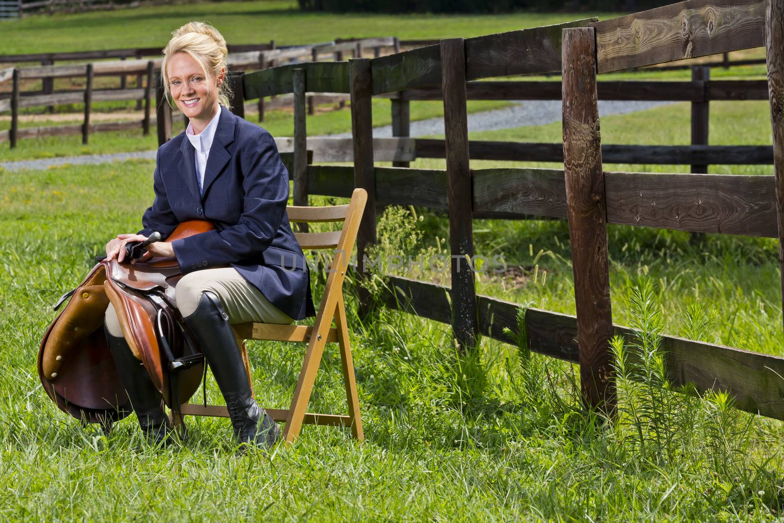 A blonde equestrian model poses outdoors before a horse show