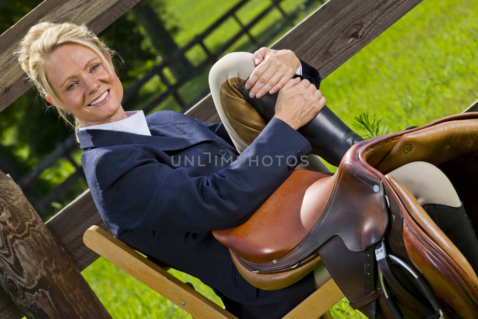 A blonde equestrian model poses outdoors before a horse show