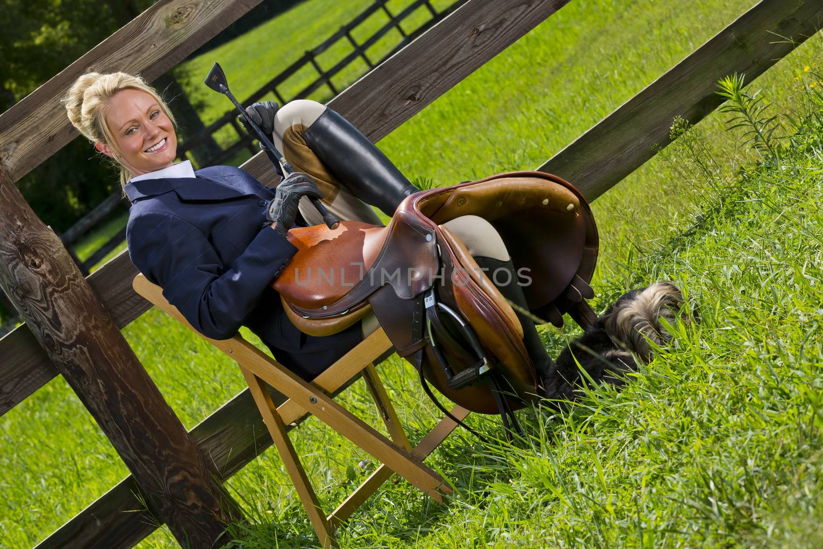 A blonde equestrian model poses outdoors before a horse show