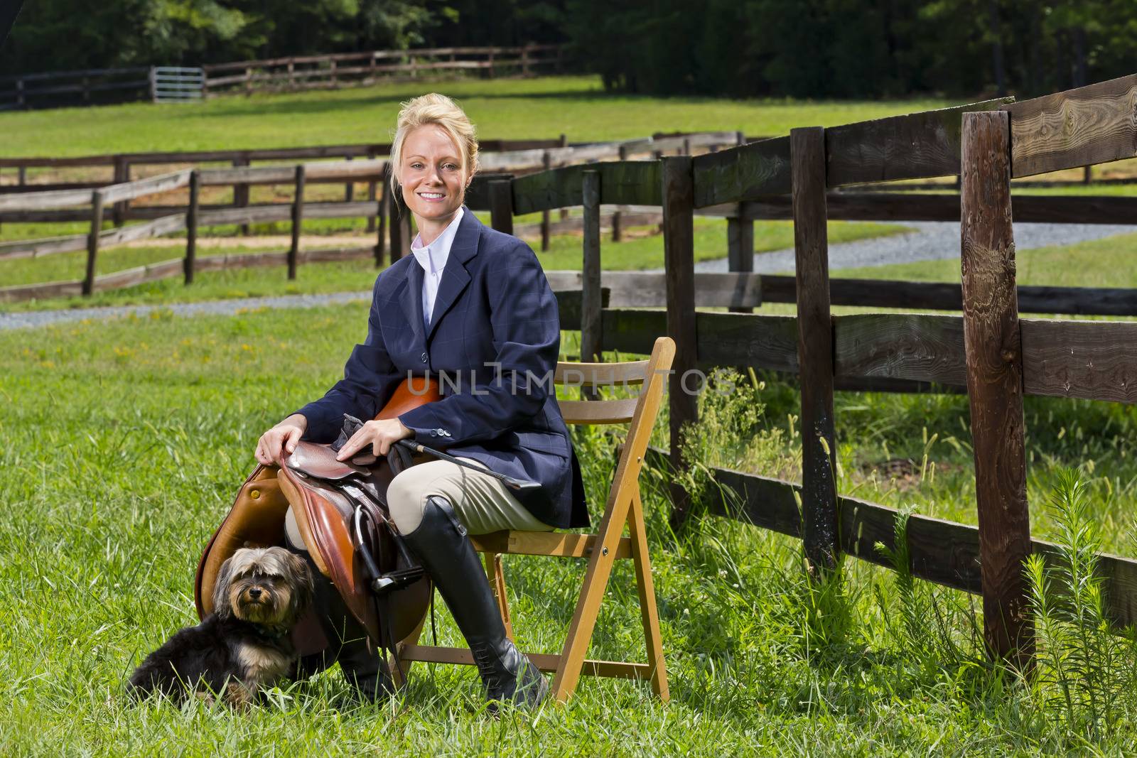 A blonde equestrian model poses outdoors before a horse show