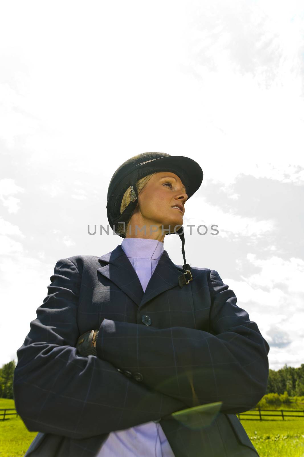 A blonde equestrian model poses outdoors before a horse show