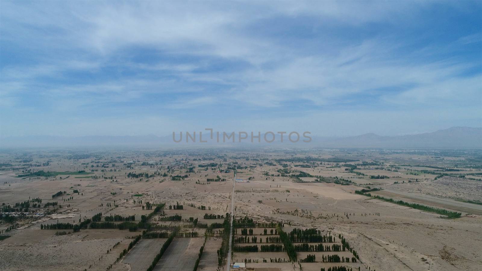 Aerial view of small poor village with school in the middle of dry farmland by Bonandbon