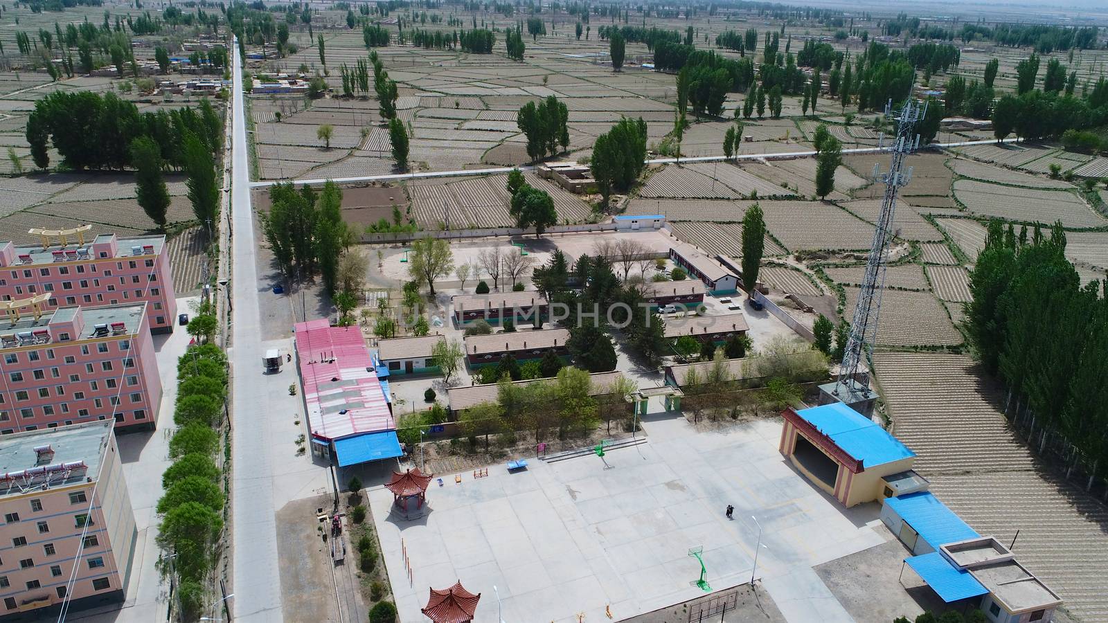 Aerial view of small poor village with school in the middle of dry farmland, Gansu, China