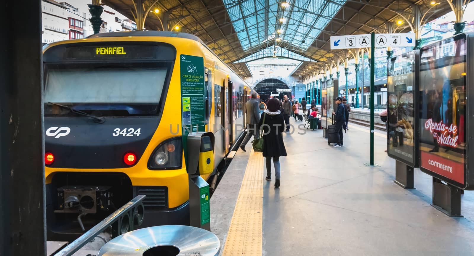 Porto, Portugal - November 30, 2018: Interior of Porto Sao Bento train station where people walk on the dock near the train stationary on a winter day