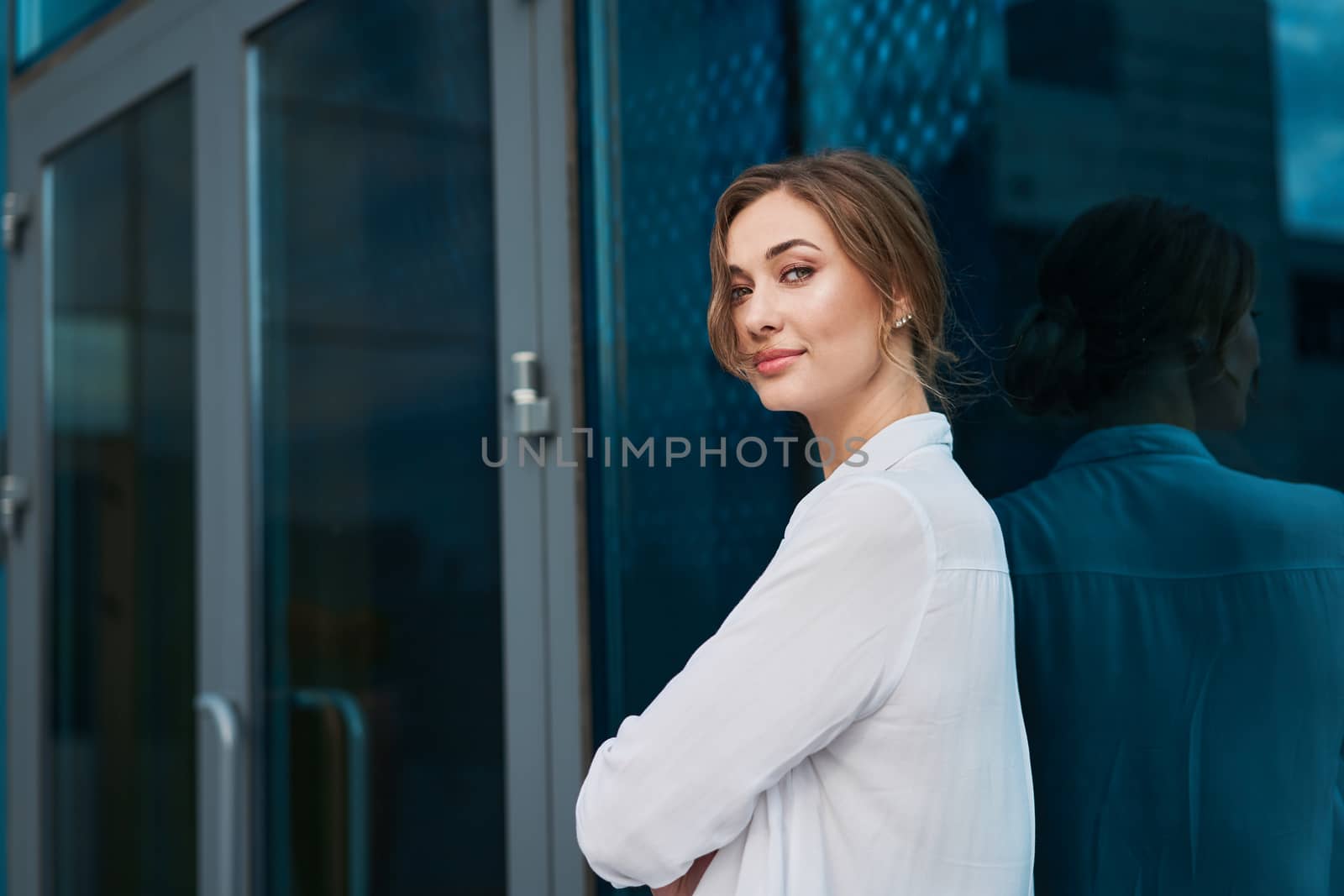 Businesswoman successful woman business person standing arms crossed outdoor corporate building exterior. Pensiv caucasian confidence professional business woman middle age by andreonegin