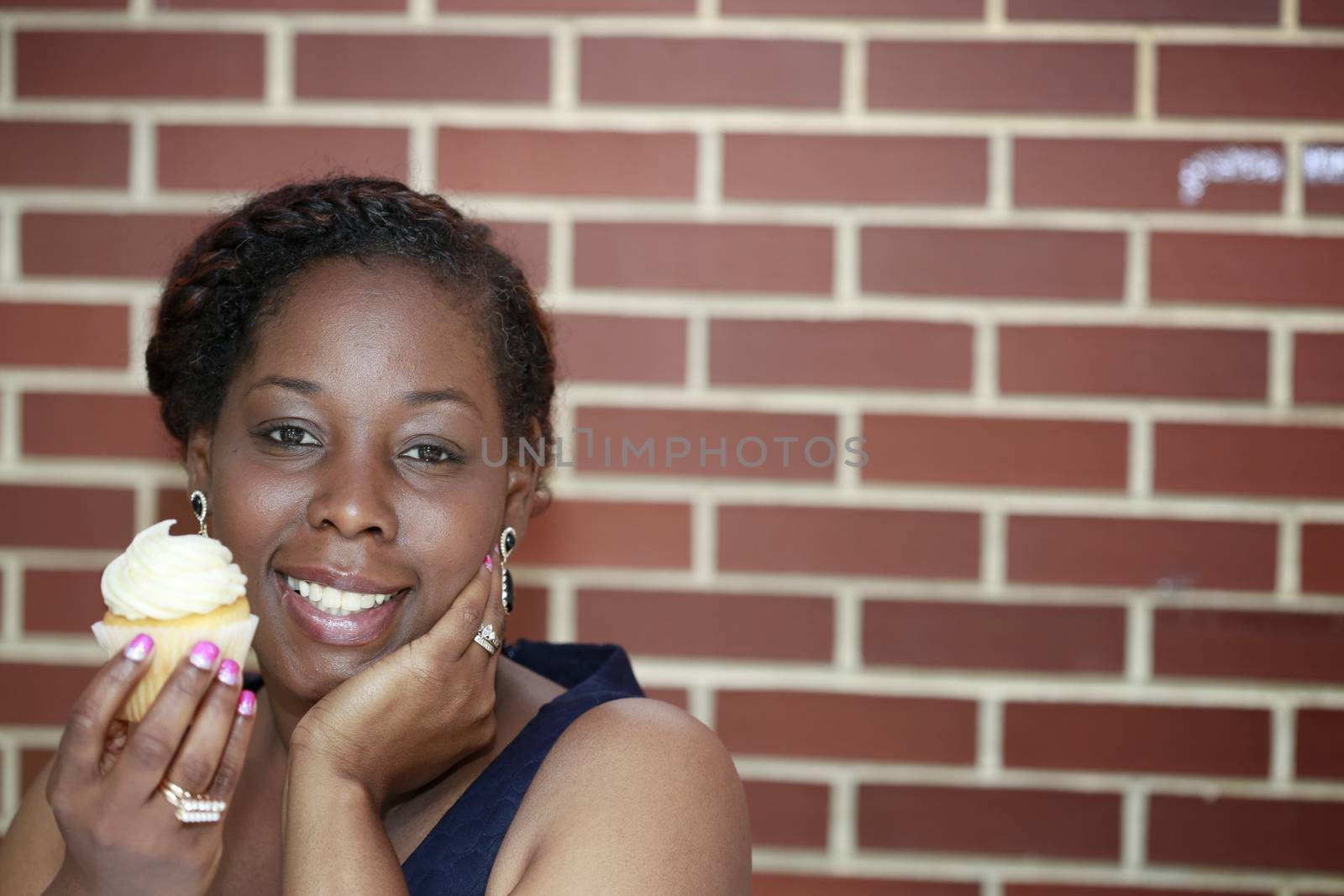 African American women holding cupcake on brick wall background