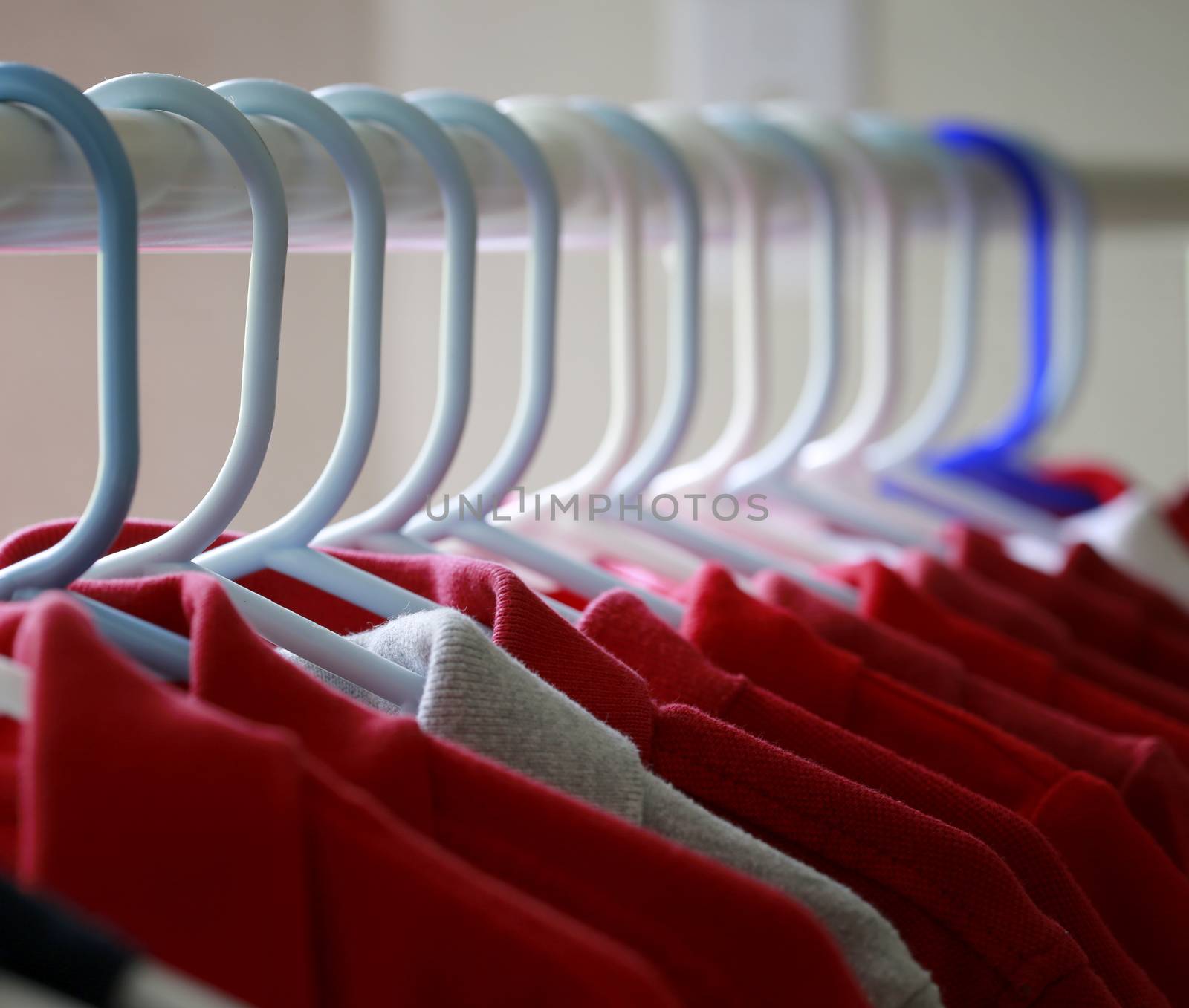 Red and one gray school uniform shirts on hangers.