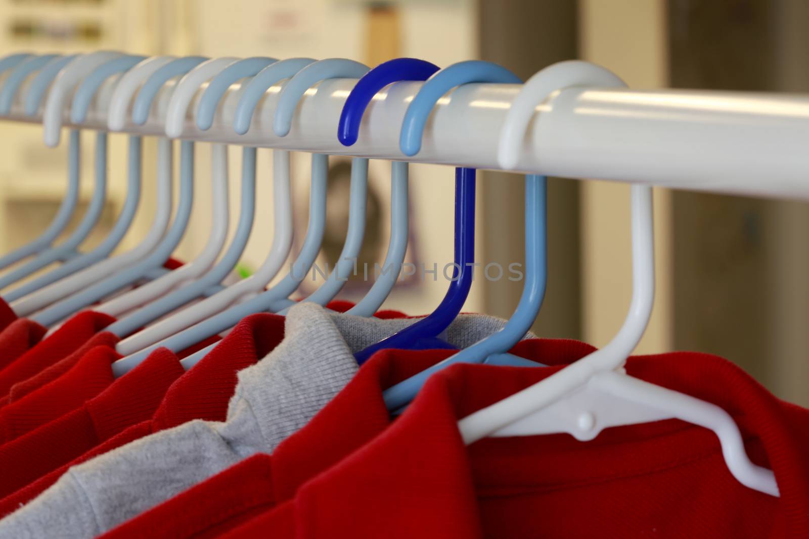 Red and one gray school uniform shirts on hangers.