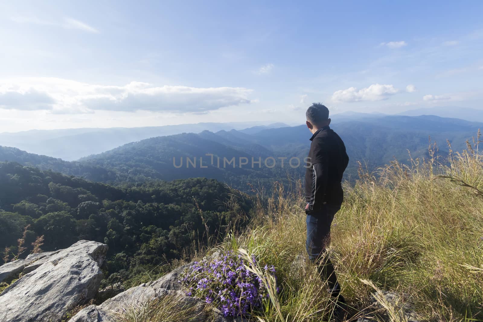 man standing on the cliff and looking at the valley and mountains in the daylight,travel concept