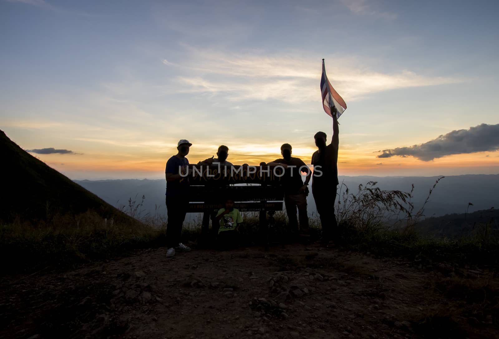 Silhouette of group of people at top of mountain at sunset