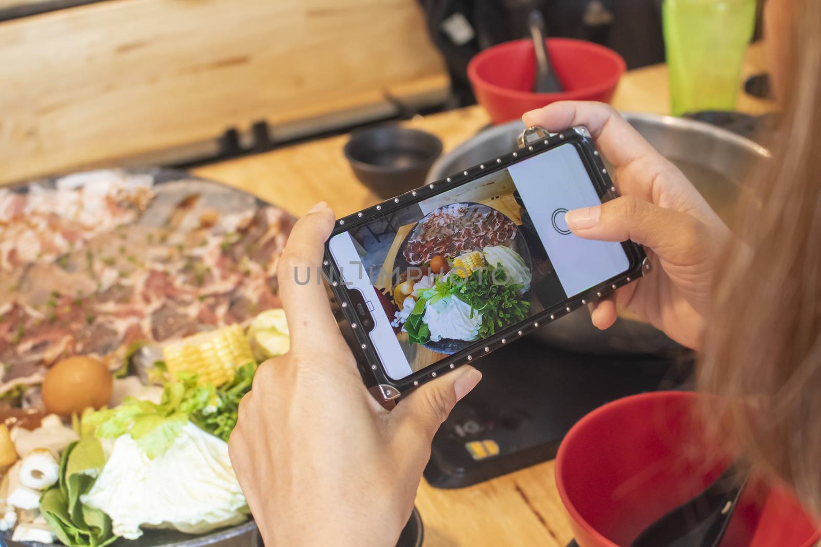 woman taking photo of sukiyaki shabu shabu with mobile smartphone