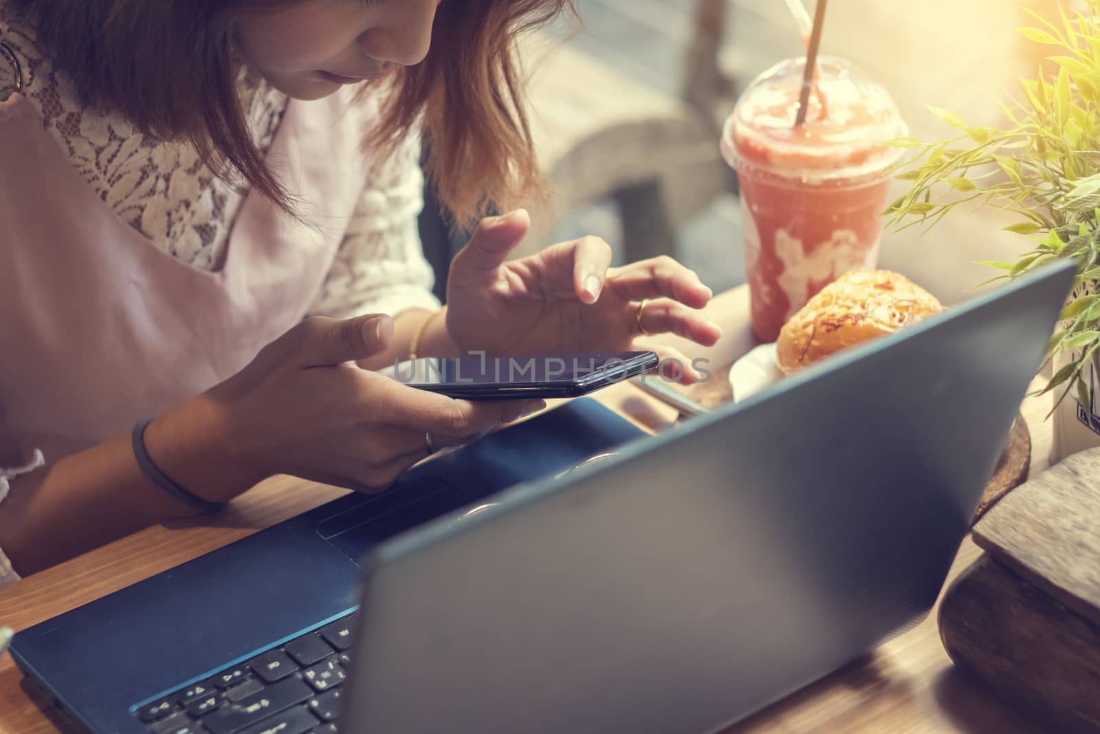 woman using smartphone in coffee shop with laptop by Gobba17