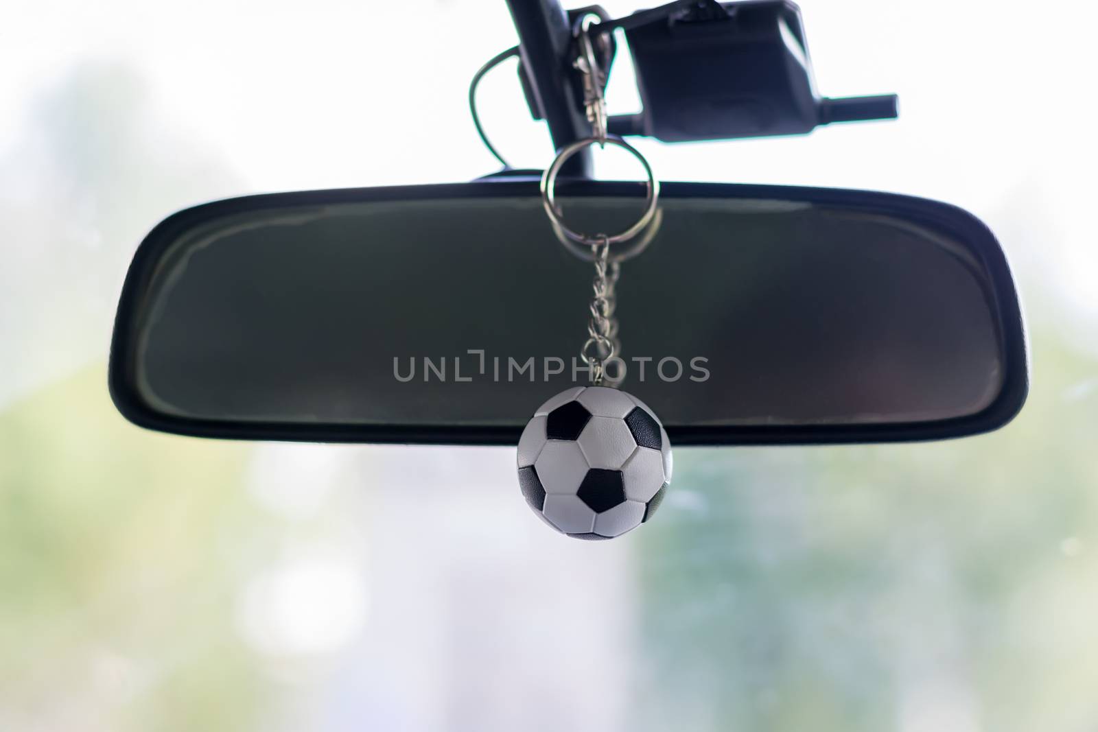 keychain small soccer ball hanging on the rear view mirror in the car near the windshield
