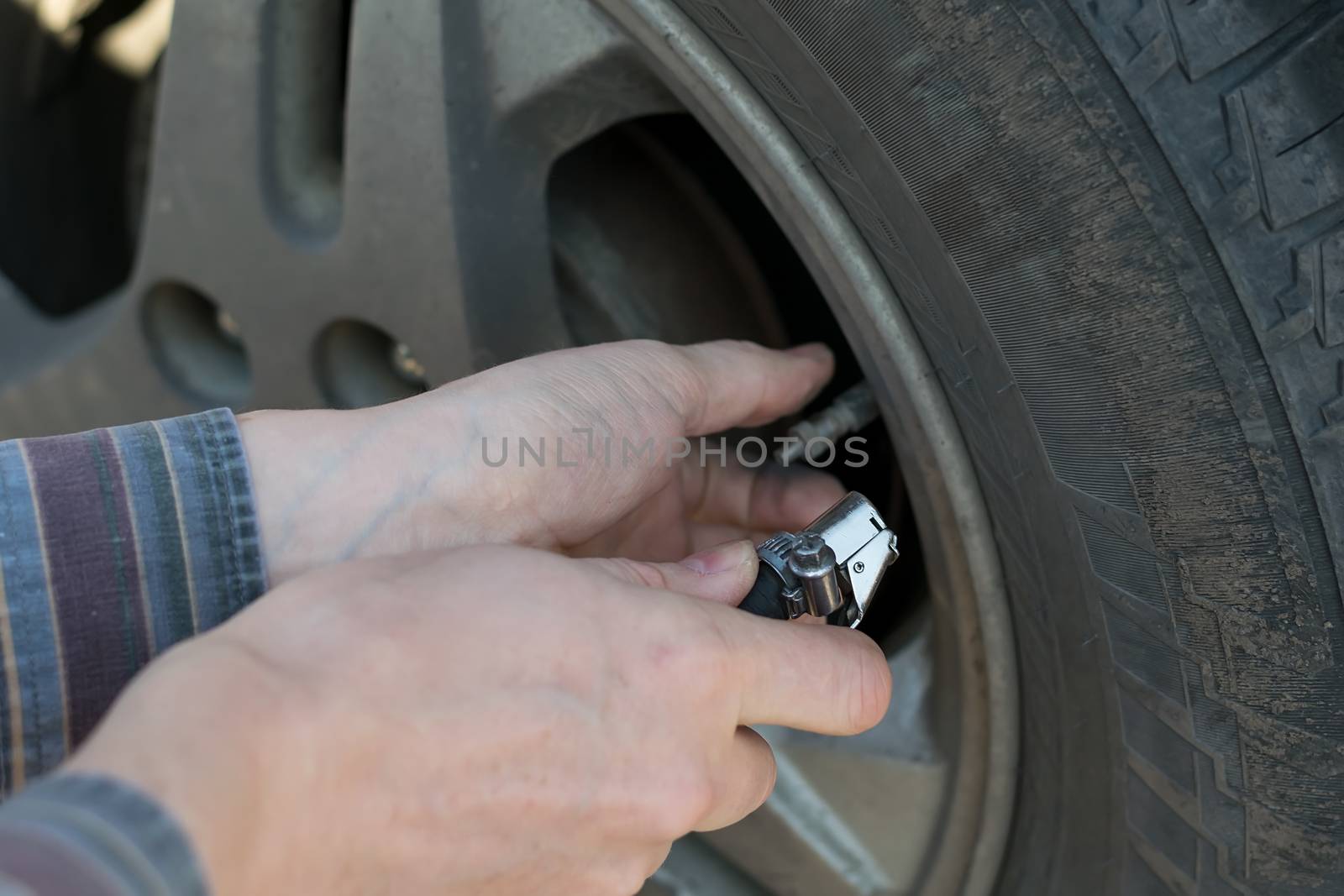 human hands insert the hose of the car pump to pump air into the wheel of the car by jk3030
