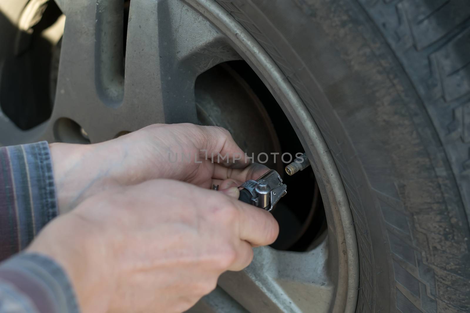 human hands insert the hose of the car pump to pump air into the wheel of the car by jk3030