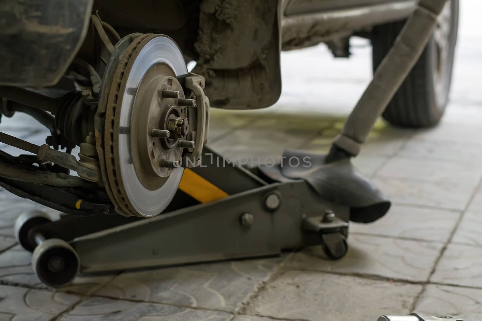 Wheel arch of the car with the removed wheel. Brake disc car wheels with caliper at the service station by jk3030